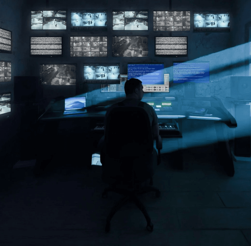 Security operator monitoring multiple live camera feeds on large screens in a dark control room